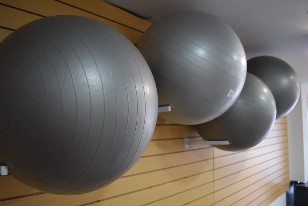 Pelotas de pilates colgadas en la pared de madera del estudio de Metanoia Pilates